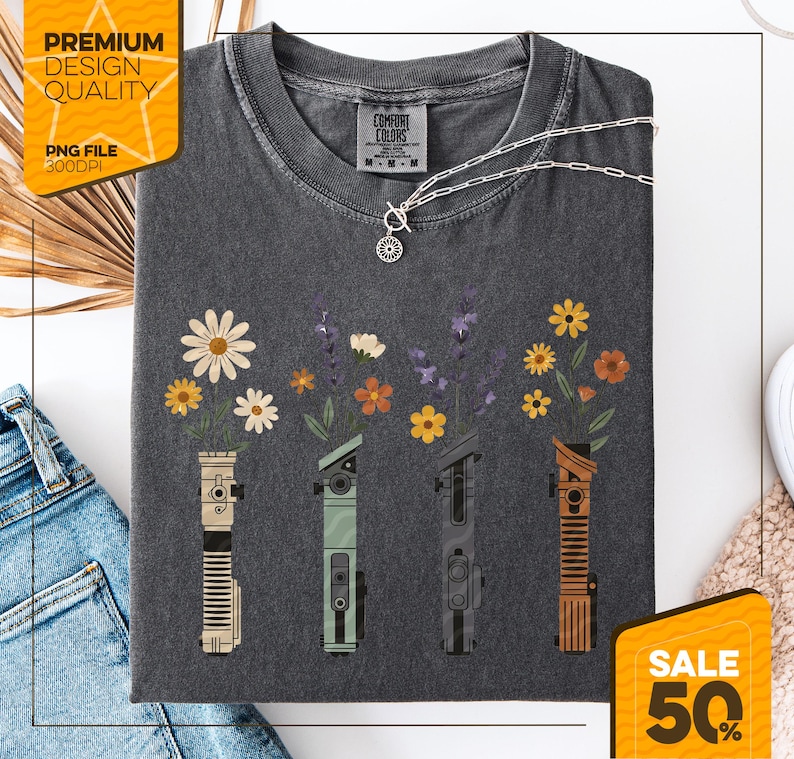 Puede incluir: Camiseta gris oscuro con un dise&ntilde;o floral. El dise&ntilde;o presenta cuatro sables de luz estilizados con flores que brotan de la parte superior. La camiseta tiene el texto "Comfort Colors" y "Premium Design Quality" con "PNG FILE 300DPI". Tambi&eacute;n se ven un collar y una pegatina "SALE 50%".