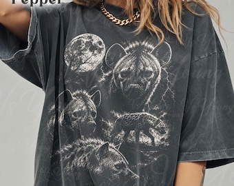 May include: A charcoal gray oversized t-shirt featuring a white graphic print of three hyenas and a full moon. The text Pepper is printed in the upper left corner, and the text VSYOUNG is printed in the lower right corner of the garment.