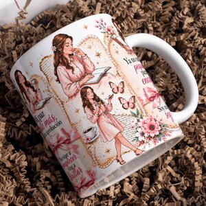 May include: A white ceramic mug featuring illustrations of a person with long brown hair wearing a pink dress, surrounded by butterflies, pink flowers, and ribbons. The mug includes Spanish text such as 'Mi paz vale más que tu aprobación' and 'No vine a complacer, vine a brillar'.
