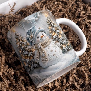 Puede incluir: Una taza de cerámica blanca con una ilustración impresa de un muñeco de nieve con gorro azul y bufanda beige, situado entre dos pinos nevados decorados con luces brillantes en un paisaje invernal con carámbanos.