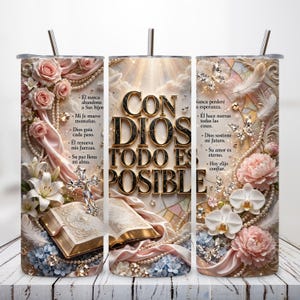 May include: A cylindrical tumbler with a straw featuring a religious design with pink roses, white lilies, orchids, pearls, butterflies, a cross, and an open book. The text reads: CON DIOS TODO ES POSIBLE, along with various Spanish phrases about faith and hope.