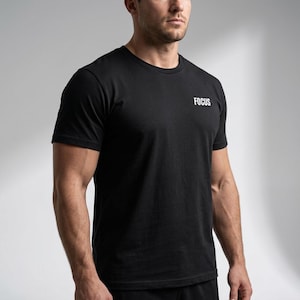 Pode incluir: T-shirt preto com gola redonda com a palavra "FOCUS" impressa em branco no peito. A camisa é de manga curta e é feita de um material macio.