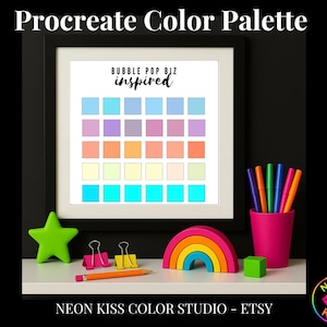 Op de afbeelding: Een ingelijste Procreate Color Palette print met een raster van pastelkleurige kleurmonsters. De print is gelabeld "Bubble Pop Biz inspired". Een groene ster, regenboog, roze beker met stiften en andere kleurrijke bureau-accessoires zijn gerangschikt op een witte plank.