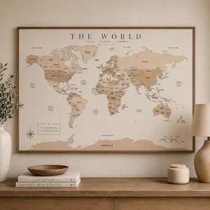 May include: A rectangular world map wall art print in shades of beige and tan with black text. The map features the title THE WORLD, the text EXPLORE DISCOVER REMEMBER EST. 2014, and a legend with symbols for places adventured and adventures to come.