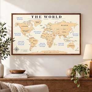 Puede incluir: Un mapa mural rectangular titulado THE WORLD en un marco de madera oscura. El mapa presenta masas terrestres de color beige con nombres de países en negro y océanos en azul. Incluye una rosa de los vientos y una leyenda de fronteras.