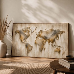 May include: A rectangular wall art piece featuring a textured world map in shades of beige, gold, and dark gray. The continents are depicted with a raised, impasto-style paint application that creates a layered, three-dimensional effect on canvas.
