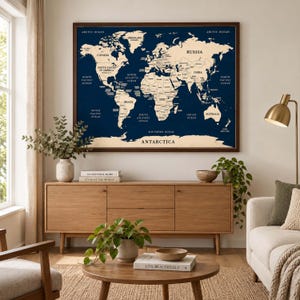May include: A large rectangular wall map featuring a dark navy blue background with cream-colored continents and oceans. The map displays country names, major bodies of water, and Antarctica at the bottom, all framed in a dark brown wooden border.