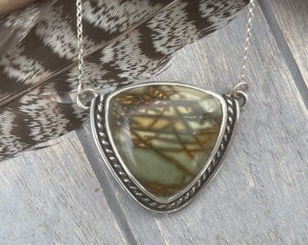May include: A silver chain necklace with a triangular pendant featuring a green and brown stone with a swirling pattern. The pendant has a silver rope-like border.