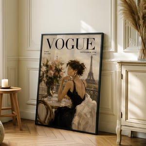 May include: Framed Vogue magazine cover art featuring a woman in a black dress, a glass of wine, and the Eiffel Tower in the background. The cover reads "VOGUE" with "Paris" and "September 15th 1952" displayed.