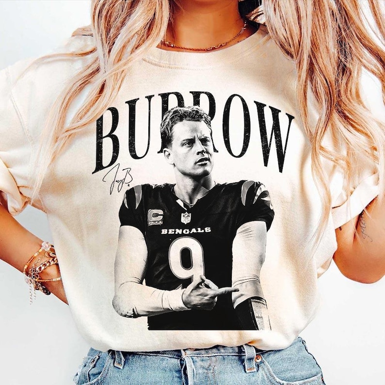 May include: A cream-coloured short-sleeve t-shirt featuring a black and white graphic of Joe Burrow in a Cincinnati Bengals jersey with the number 9. The text BURROW is printed in a large, distressed black font above the image, with a signature.