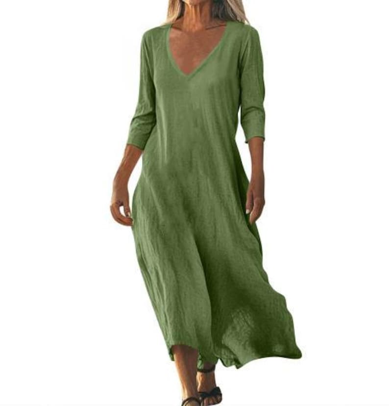 May include: A green, V-neck dress with three-quarter sleeves. The dress has a loose, flowing design and falls to mid-calf length. The fabric appears to be a lightweight linen or cotton blend, suitable for warm weather.