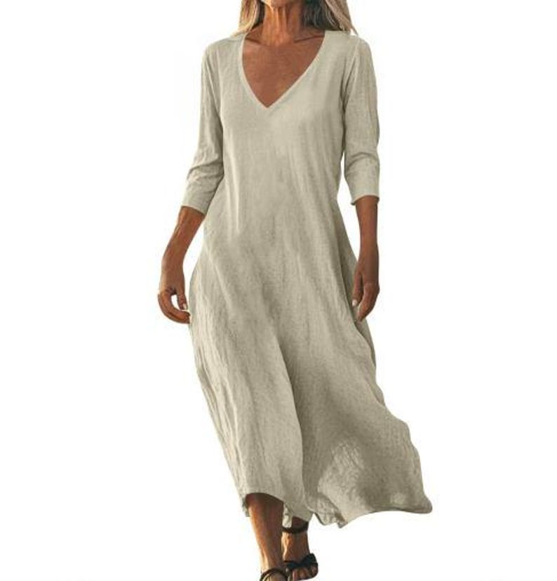 May include: A beige, V-neck dress with three-quarter sleeves. The dress has a loose, flowing silhouette and falls to mid-calf. The fabric appears to be a lightweight linen or cotton blend, suitable for warm weather.