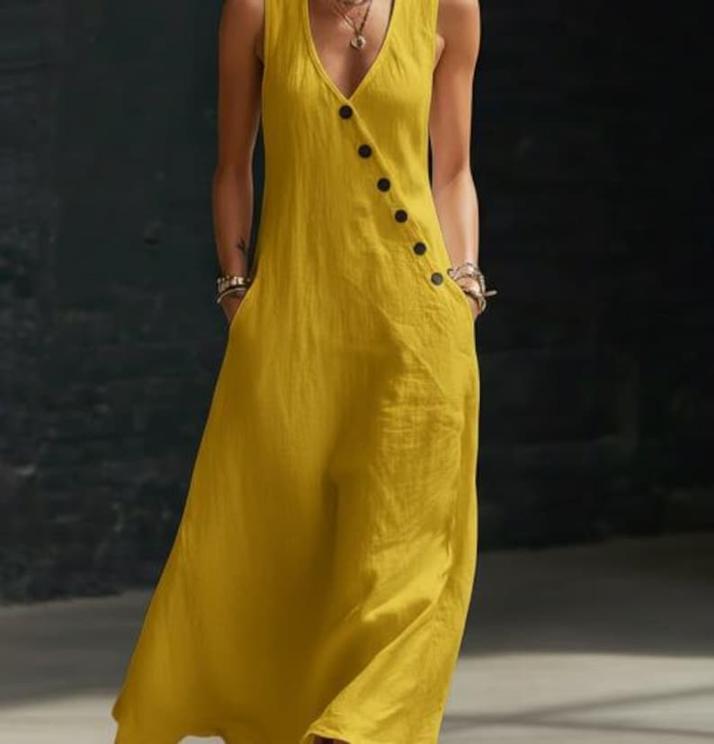 May include: A sleeveless, mustard yellow dress with a V-neckline and a row of black buttons down the side. The dress has two front pockets and a flowing, relaxed fit, suitable for warm weather.