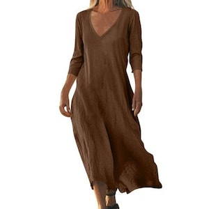 May include: A brown, V-neck dress with three-quarter sleeves. The dress has a loose, flowing silhouette and falls to the mid-calf. The fabric appears to be a lightweight material, suitable for warmer weather. The dress is a solid color with no visible patterns.