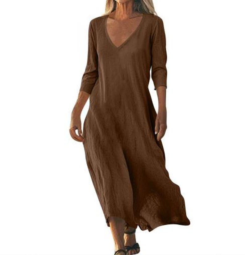 May include: A brown, V-neck dress with three-quarter sleeves. The dress has a loose, flowing silhouette and falls to the mid-calf. The fabric appears to be a lightweight material, suitable for warmer weather. The dress is a solid color with no visible patterns.