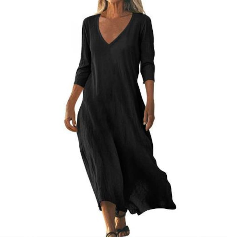 May include: A black, long-sleeve dress with a V-neck. The dress has a loose, flowing design and falls to mid-calf. The fabric appears to be a lightweight material, suitable for warmer weather. The dress is a solid black color.