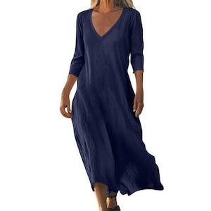 May include: A navy blue, long-sleeve dress with a V-neck. The dress has a flowing, relaxed fit and falls to the mid-calf. The fabric appears to be a lightweight linen or cotton blend, suitable for warm weather.