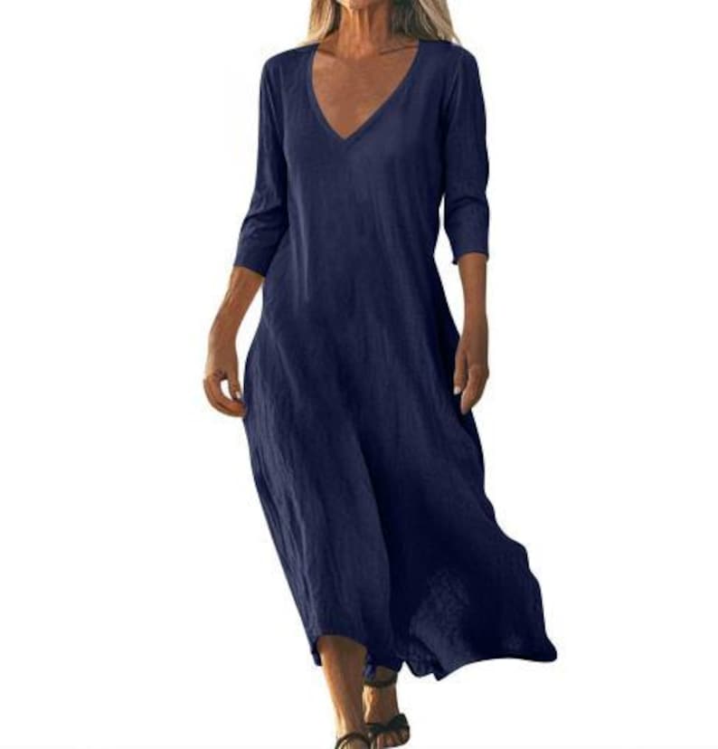 May include: A navy blue, long-sleeve dress with a V-neck. The dress has a flowing, relaxed fit and falls to the mid-calf. The fabric appears to be a lightweight linen or cotton blend, suitable for warm weather.