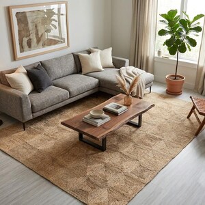 May include: A grey sectional sofa with cream and dark grey throw pillows, a live-edge wooden coffee table with black metal legs, and a large rectangular woven jute rug with a geometric pattern, positioned in a room with a floor lamp and plant.