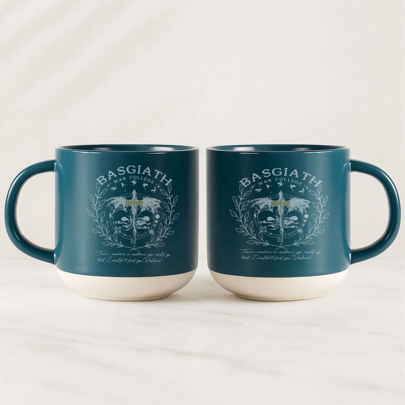 May include: Two teal ceramic mugs with white bottoms. Each mug features the text "BASGIATH WAR COLLEGE" above a crest design. Below the crest is the quote, "There's nowhere in existence you could go that I couldn't find you, Valoria."