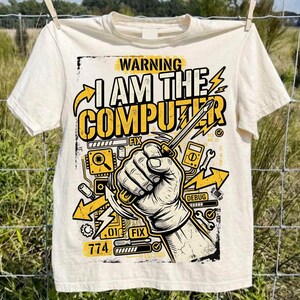 Może przedstawiać: Kremowy t-shirt z nadrukiem graficznym przedstawiającym dłoń trzymającą śrubokręt. Tekst głosi WARNING I AM THE COMPUTER. Dodatkowe elementy graficzne to żółte strzałki, błyskawice, ikony płytek drukowanych oraz napisy FIX i DEBUG.
