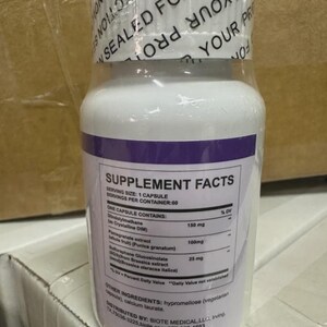 May include: White supplement bottle with a purple band and a white lid. The label includes "Supplement Facts" and ingredient information. The bottle is sealed for protection.