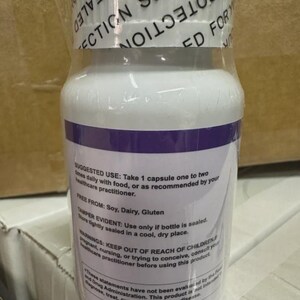 May include: A white supplement bottle with a purple band and clear plastic wrap. The label includes text about suggested use, ingredients, and warnings. The top of the bottle is sealed with a white band that reads "PROTECTION SEALED FOR YOUR".