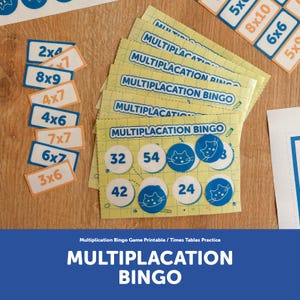 May include: A Multiplication Bingo game set featuring yellow grid-patterned cards with the text 'MULTIPLACATION BINGO'. The set includes blue and orange rectangular equation tiles and blue circular tokens with white cat face illustrations.