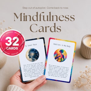 May include: Mindfulness Cards with 32 cards, featuring two cards with illustrations and text. One card has a blue and white silhouette, the other a colorful illustration. A lit candle and a small vase with dried flowers are also visible.
