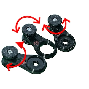 Puede incluir: Tres accesorios de cámara negros, impresos en 3D, con almohadillas de montaje circulares y un orificio central. Flechas rojas indican el movimiento de rotación. Cada pieza tiene un pequeño logotipo. El fondo es blanco.