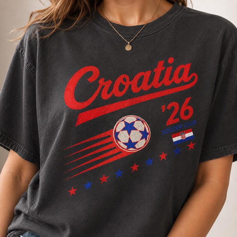 Puede incluir: Una camiseta gris carb&oacute;n con el texto rojo Croatia sobre un gr&aacute;fico de un bal&oacute;n de f&uacute;tbol con l&iacute;neas de movimiento. El dise&ntilde;o incluye el texto '26, las palabras SOCCER CLUB, una peque&ntilde;a bandera croata y una fila de estrellas rojas y azules.