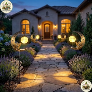 May include: Garden pathway lights with a crescent moon design, bird silhouette, and star cutouts. Each light has a glowing orb. The lights are set along a stone pathway leading to a house at dusk. The lights are from Tiny Gnome Garden.