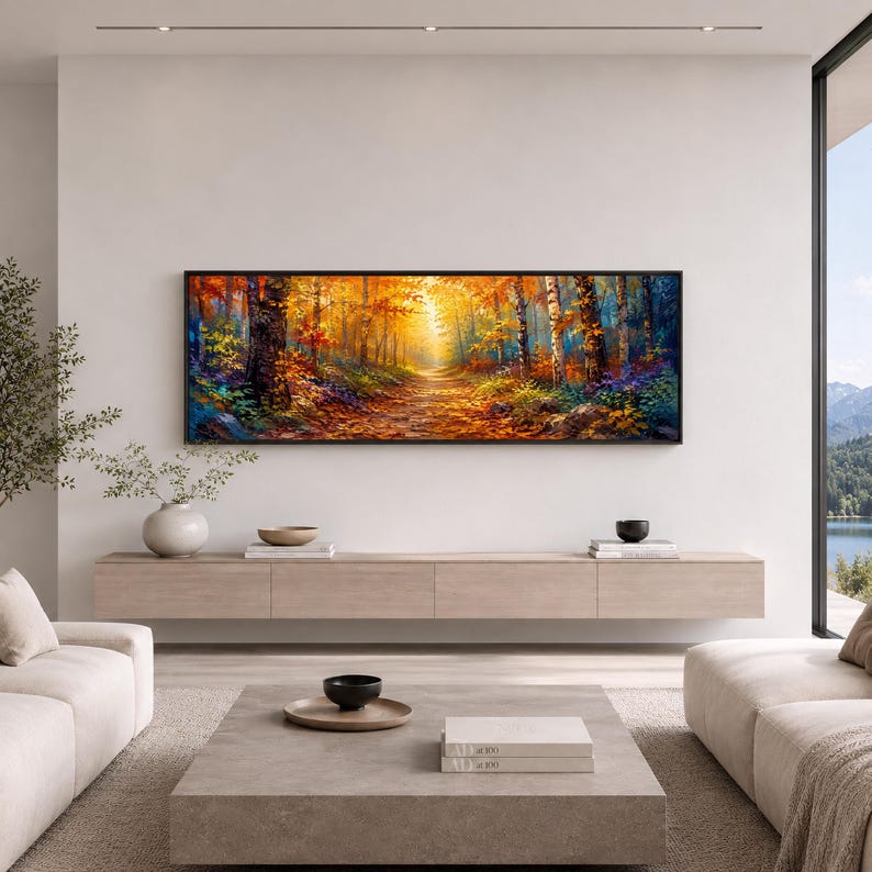 May include: A rectangular landscape painting featuring a forest path during autumn. The scene displays vibrant orange, yellow, and red foliage on trees, with a sunlit trail leading into the distance. The artwork is framed in a thin black border.