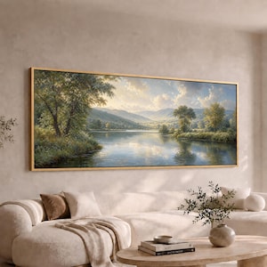 May include: A panoramic landscape painting in a thin gold frame depicting a serene river flowing through a lush valley. The scene features green trees along the banks, rolling hills in the distance, and a soft, cloudy sky reflecting on the water.
