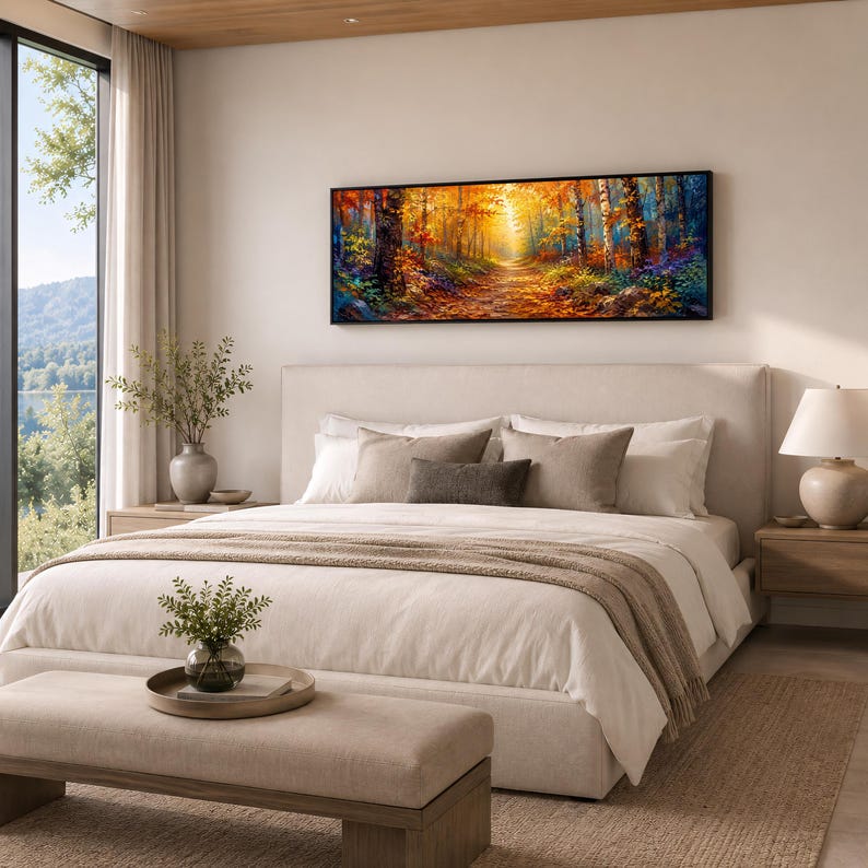 May include: A panoramic rectangular wall art print featuring a vibrant autumn forest scene with golden sunlight filtering through trees, displayed in a black frame above a neutral-toned upholstered bed in a bedroom setting.