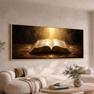 May include: A panoramic wall art print featuring an open book resting on a dark, textured wooden surface. Golden light beams shine down from above onto the pages, creating a high-contrast scene with deep shadows and warm, glowing highlights.