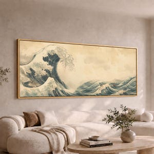 May include: A rectangular wall art print featuring a large, stylized ocean wave in shades of deep blue and white against a muted, cream-colored background. The artwork is enclosed in a thin, light-toned wooden frame, displaying a panoramic view.