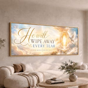 May include: A rectangular wall art piece in a gold frame featuring a sky scene with clouds, a bright light, and a white dove. The text reads: He will WIPE AWAY EVERY TEAR REVELATION 21:4. The artwork is displayed above a beige sofa and coffee table.
