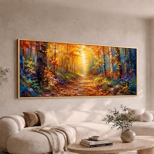 May include: A wide rectangular landscape painting in a thin wooden frame depicting a forest path during autumn. The scene features tall trees with vibrant orange, yellow, and red foliage, a sunlit trail covered in fallen leaves, and deep blue shadows.