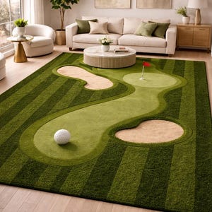 May include: A green golf course-themed rug featuring a golf ball, sand traps, and a flag on the green. The rug has a striped fairway design and is placed in a living room. A unique home decor item, the rug measures approximately 240 cm x 300 cm.