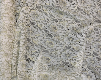 May include: White lace fabric with a gold metallic thread woven into the design. The lace has a floral pattern.