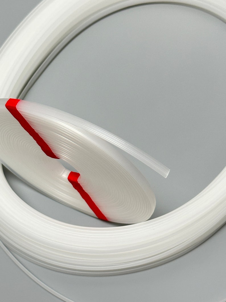 Pu&ograve; includere: Una striscia di rivestimento in plastica bianca arrotolata in un cerchio. La striscia di rivestimento &egrave; avvolta da un nastro rosso.