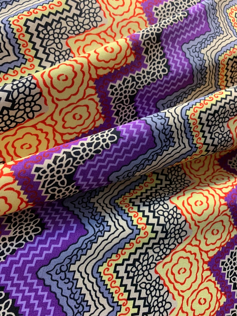 May include: Purple, yellow, red, and black geometric patterned fabric with a zig-zag design.