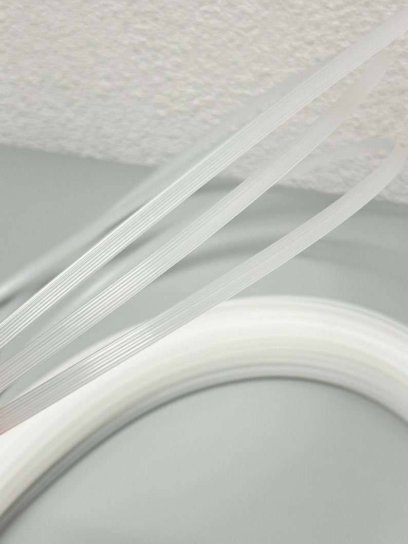 Pu&ograve; includere: Tre cursori per cerniera in plastica bianca, ognuno con una serie di creste parallele, sono disposti in uno schema curvo.
