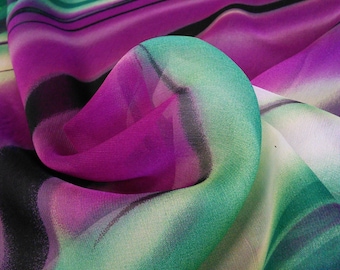 May include: A close-up of a fabric with a colorful striped pattern. The fabric is a blend of green, purple, and white stripes with black accents. The fabric is soft and flowing, and it has a subtle sheen.