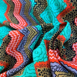 May include: A colorful fabric with a geometric pattern in shades of turquoise, red, black, and gold. The fabric has a wavy, flowing texture.