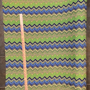 May include: Green, blue, and yellow fabric with a chevron pattern. The fabric is 43 inches wide and has a repeating pattern of small circles.
