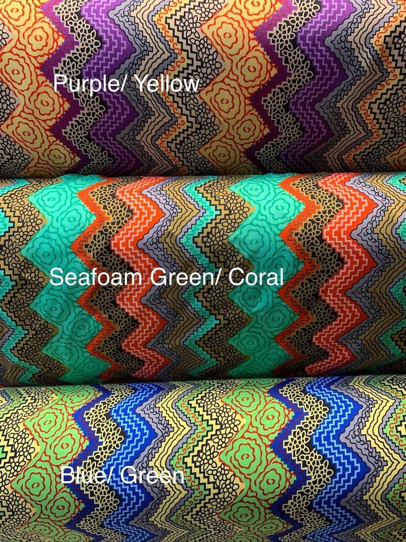 May include: Three rolls of fabric with a zig-zag pattern in different color combinations. The top roll is purple and yellow, the middle roll is seafoam green and coral, and the bottom roll is blue and green.  The fabric has a small floral pattern.