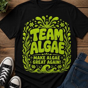May include: A black short-sleeved t-shirt featuring a bright lime green graphic print. The design includes the text "TEAM ALGAE" and "MAKE ALGAE GREAT AGAIN!" surrounded by stylised seaweed, bubbles, and wave patterns in a vibrant green colour.