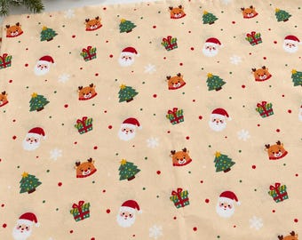 Op de afbeelding: Een beige stof met een herhalend kerstpatroon van kerstmangezichten, rendierkoppen, groene dennenbomen en kleurrijke cadeautjes, afgewisseld met kleine rode en groene stippen en witte sneeuwvlokken.